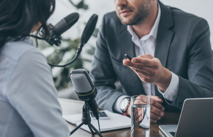 A man and woman in business suits conversing on a microphone during a professional event.